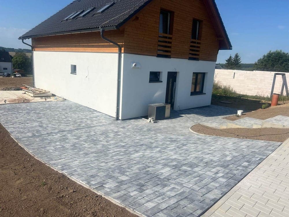 Nová šedá zámková dlažba kolem dokončeného rodinného domu